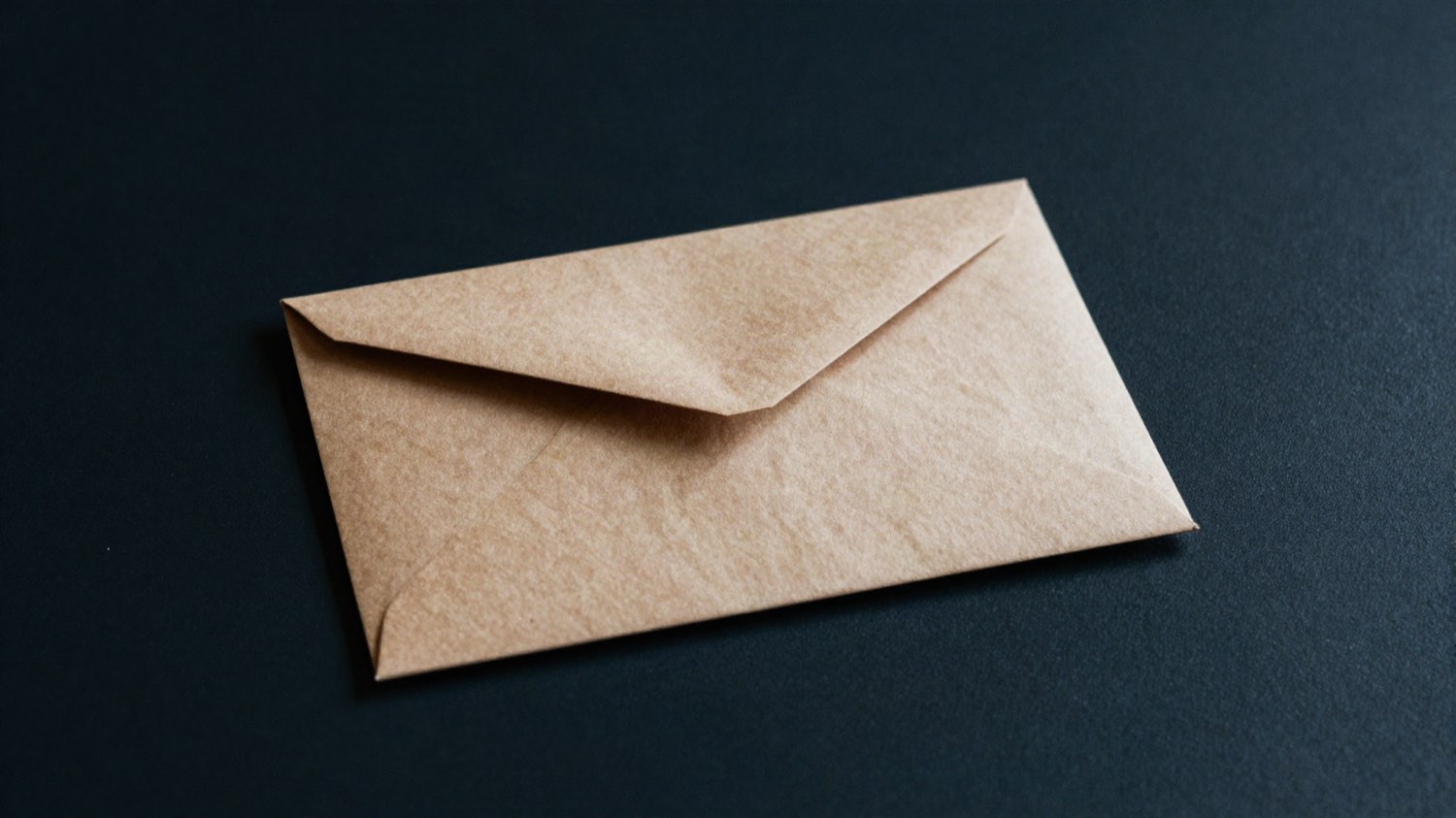 Une enveloppe kraft fermée, seule sur un bureau sombre, avec une ombre portée nette