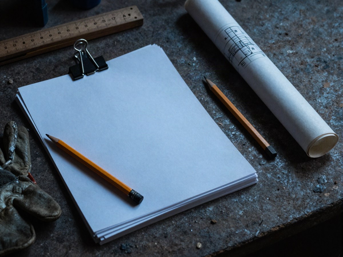 Un bloc de feuilles vierges, un mètre pliant et un crayon sur un établi